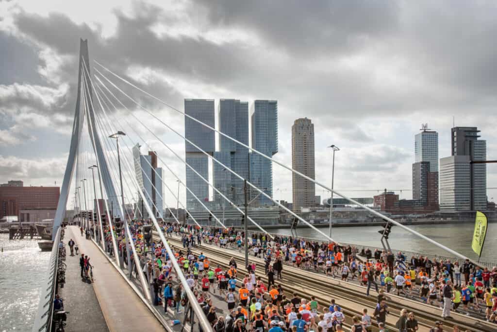 Drukke hardloopwedstrijd over Erasmusbrug in Rotterdam, sportevenement, hardlopen, stadsrace, gezondheidsbevordering.